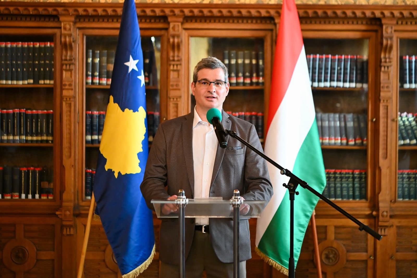 Csaplár-Degovics Krisztián beszédet tart Koszovó és Magyarország zászlói előtt állva a budapesti Szabó Ervin Könyvtárban.